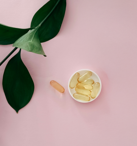 Capsules de compléments alimentaires naturels dans une coupelle, feuilles vertes