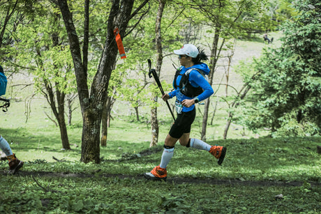 Coureuse de trail avec bâtons en forêt
